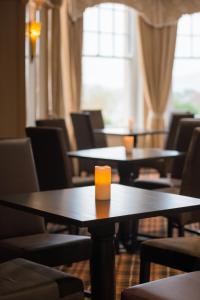 a row of tables and chairs with a candle on them at Royal Victoria Hotel Snowdonia in Llanberis