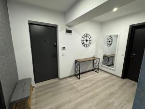 a hallway with a door and a table and a clock at 1 Mai - Luxury Park Apartments - Self check-in - Private parking 3 in Craiova