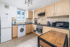 La cuisine est équipée d'un réfrigérateur blanc et d'un lave-vaisselle. dans l'établissement Warm & Cosy Flat in King Cross, à Londres