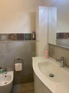 un bagno con lavandino, WC e specchio di La casa di Ely a Viareggio