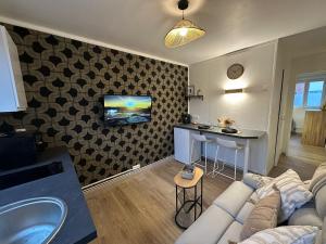 ヴァランシエンヌにあるLeRelaisdOdile - Studio Confort - Proche Hôpital - Idéal Couple & Travailleur- Accès Autoroute Rapideのソファと壁掛けテレビのあるリビングルーム