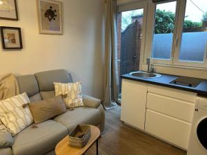 ヴァランシエンヌにあるLeRelaisdOdile - Studio Confort - Proche Hôpital - Idéal Couple & Travailleur- Accès Autoroute Rapideのソファと洗面台のあるリビングルーム