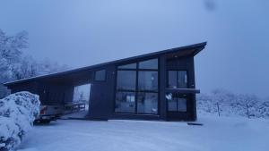 a black building with snow on the ground at Emai in Las Trancas