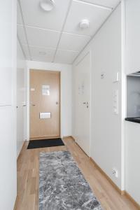 a hallway with white walls and a door and a rug at Modern 1BR Apartment in Kaleva next to Tram Line in Tampere