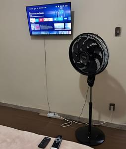 un ventilatore nero su un supporto di fronte a una TV di Casa 5 quartos entre Centro e Pampulha a Belo Horizonte Altre 37 foto