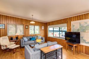 a living room with wood paneling and a tv at Taupo Bay Beach House in Totara North