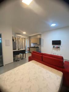 uma sala de estar com um sofá vermelho e uma televisão em Studio para locação Pereque-Açu em Ubatuba