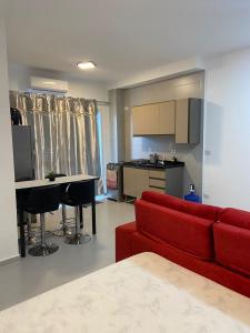 uma sala de estar com um sofá vermelho e uma cozinha em Studio para locação Pereque-Açu em Ubatuba