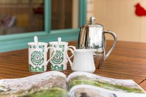 a table with three candles and a tea pot and a book at Taupo Bay Beach House in Totara North