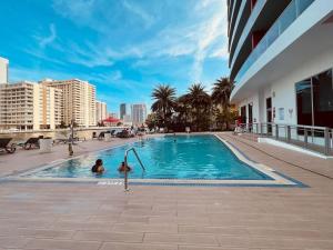 dos personas en una piscina en un edificio en Amazing Family Studio at Beachwalk on Hallandale, en Hallandale Beach