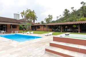 a backyard with a swimming pool and a house at Casa na Marina com piscina churrasqueira e píer in Guarujá