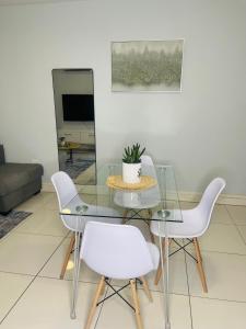 a dining room with a glass table and white chairs at Windhoek Cozy stay in Windhoek