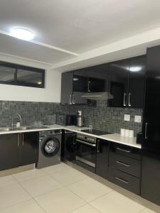a kitchen with black cabinets and a washing machine at Windhoek Cozy stay in Windhoek +3 photos
