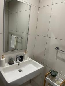 a white bathroom with a sink and a mirror at Windhoek Cozy stay in Windhoek