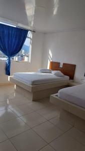 two beds in a room with a window at Hotel Ibiza in Armenia