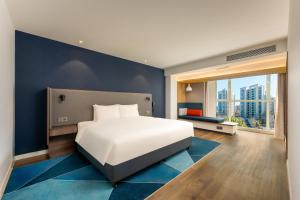 a bedroom with a white bed and a blue wall at Holiday Inn Express Tianjin Airport East by IHG in Tianjin +113 photos