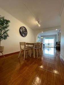 ein Esszimmer mit einem Tisch und einer Uhr an der Wand in der Unterkunft Apartamento en el centro urbano in Vilanova i la Geltrú