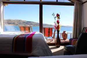a room with a bed and a vase with flowers in it at TITICACA ISLAND LODGe in Puno