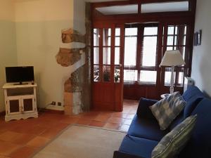 a living room with a blue couch and a tv at Finca Artienza in Ramales de la Victoria