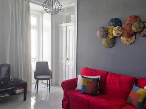 a living room with a red couch and plates on the wall at Chiado Lisbon Apartment in Lisbon