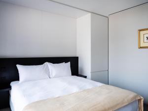 a bedroom with a white bed with a black headboard at The Conservatory in Hobart