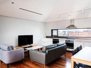 a living room with a couch and a tv at The Conservatory in Hobart