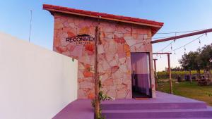a stone building with a door and a sign on it at Chalé Henri Salvador na Vinícola Reconvexo in Morro do Chapéu