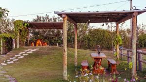 a wooden pergola with benches in a garden at Chalé Henri Salvador na Vinícola Reconvexo in Morro do Chapéu