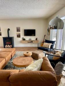 a living room with couches and a table and a television at Nell's Mountain Lodge - Arcade Hottub Fire Pit 5 Acres in Golden +39 photos