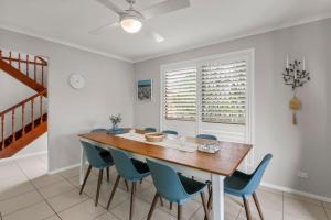 a dining room with a wooden table and blue chairs at Bren Place, 6, Battery Hill in Caloundra
