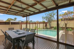 a patio with a table and chairs next to a swimming pool at Bren Place, 6, Battery Hill in Caloundra