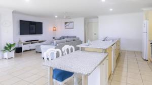 a kitchen and living room with a couch and a tv at Fernando's Beach Hideaway in Banksia Beach