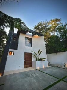 a white house with a wooden door and a plant at Stunning Villa in the heart of La Veleta in Tulum