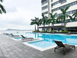 a swimming pool with chairs and a building at Suite en Puerto Santa Ana ,Torres Bellini in Guayaquil