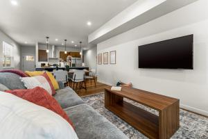 ein Wohnzimmer mit einem Sofa und einem Fernseher an der Wand in der Unterkunft The Downtown Duplex - Pet Friendly - NEW BUILD in Colorado Springs