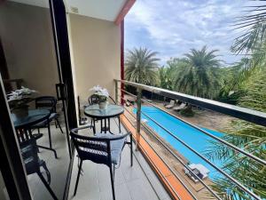 a balcony with tables and chairs and a view of a pool at Mai Khao Serenity in Ban Mai Salae