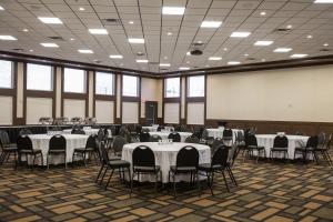 un salón de banquetes con mesas y sillas blancas en Chateau Nova Peace River, en Peace River