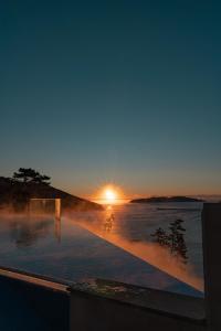 巨济Hotel SANG SANG & Private SANG SANG POOL VILLA的日出在水体上,太阳落山
