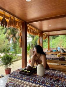 a woman sitting at a table with a plate of food at Cao bành Homestay in Ha Giang