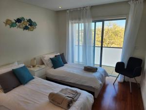 a bedroom with two beds and a chair and a window at Casa Rogel by Armação de Pêra with Heated Pool and Games Room in Alcantarilha +40 photos