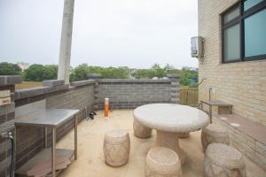 a patio with a table and stools on a building at 98Guesthouse in Jincheng