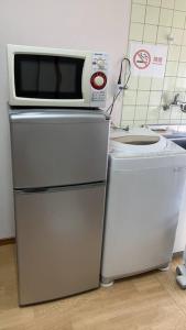 a microwave on top of a refrigerator in a kitchen at PHEBE3osaka in Osaka