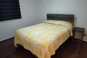 a bedroom with a bed with a yellow bedspread at Casa acogedora puertas del Mar in La Serena