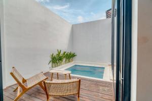 a balcony with a swimming pool and two chairs at Villa Rosie 1BR Brand New Villa In Kerobokan in Kerobokan