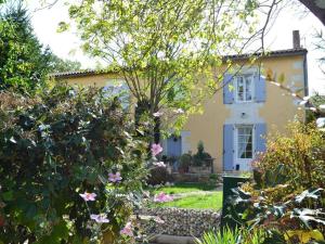 żółty dom z niebieskim oknem i kilkoma kwiatami w obiekcie Gîte familial avec jardin au bord de l'eau, terrasses, vélo, jeux, proche Charente, WiFi inclus - FR-1-653-189 w mieście Saint-Genis-dʼHiersac