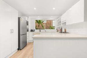 eine Küche mit weißen Schränken und einem Kühlschrank in der Unterkunft Tide's Edge by Experience Jervis Bay in Vincentia + 16 Fotos