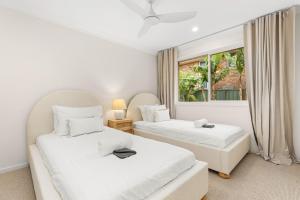 zwei Betten in einem Zimmer mit Fenster in der Unterkunft Tide's Edge by Experience Jervis Bay in Vincentia