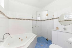 a white bathroom with a tub and a mirror at Bobby's Beachside Bungalow in Grange in Grange +12 photos