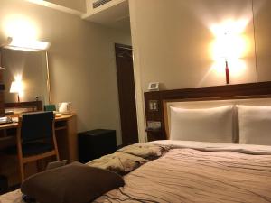 a bedroom with a bed with a desk and a mirror at Kanazawa Manten Hotel Ekimae in Kanazawa