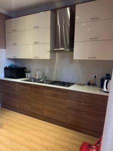 a kitchen with wooden cabinets and a sink and a stove at Central Park Apartment in Tbilisi City